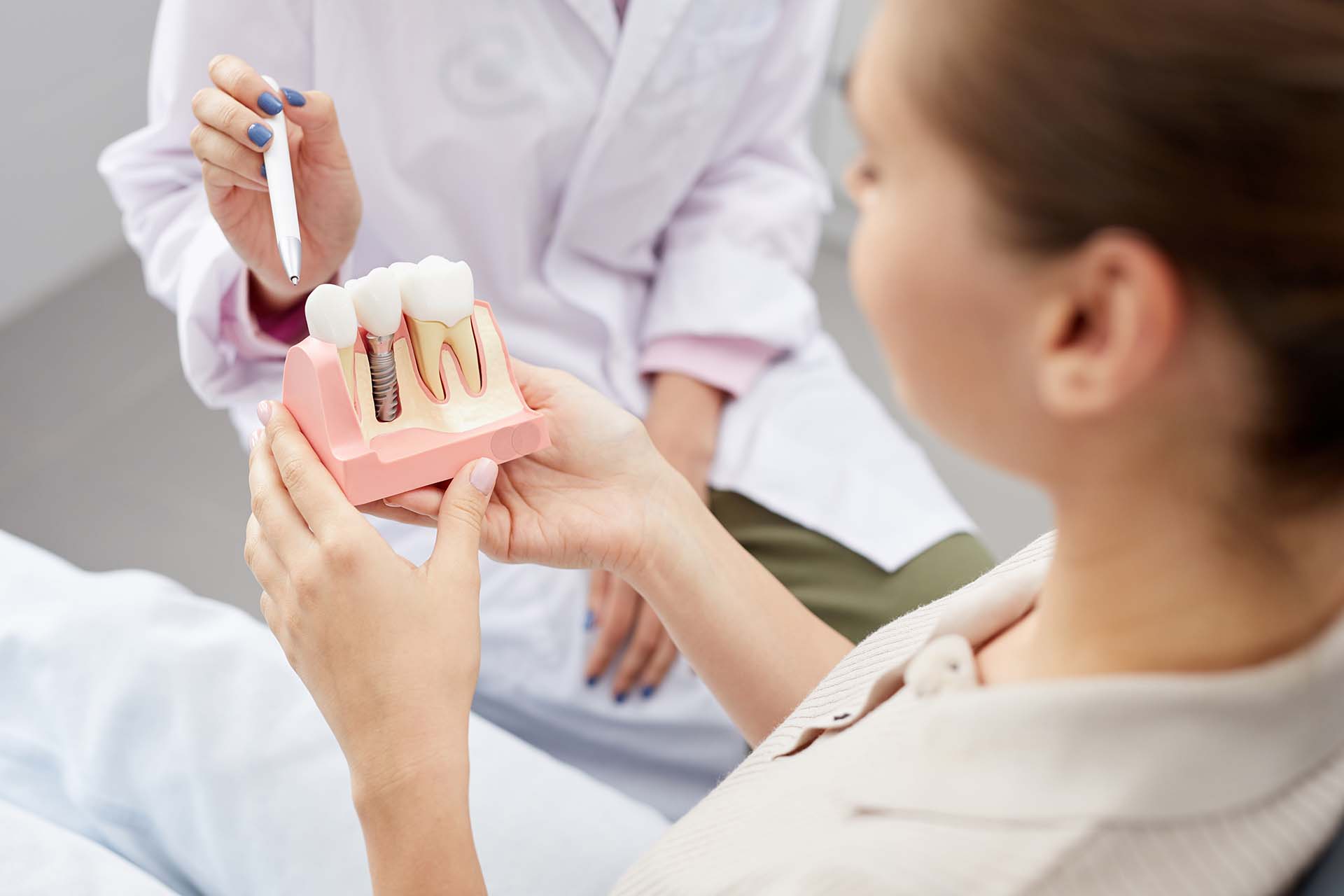 female doctor pointing at tooth model while consulting patient, copy space