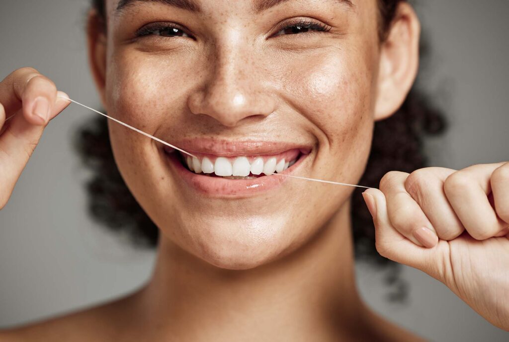Woman portrait, dental floss and flossing teeth with smile for oral hygiene, health and wellness on studio background. Face of female happy about self care, healthcare and grooming for healthy mouth.