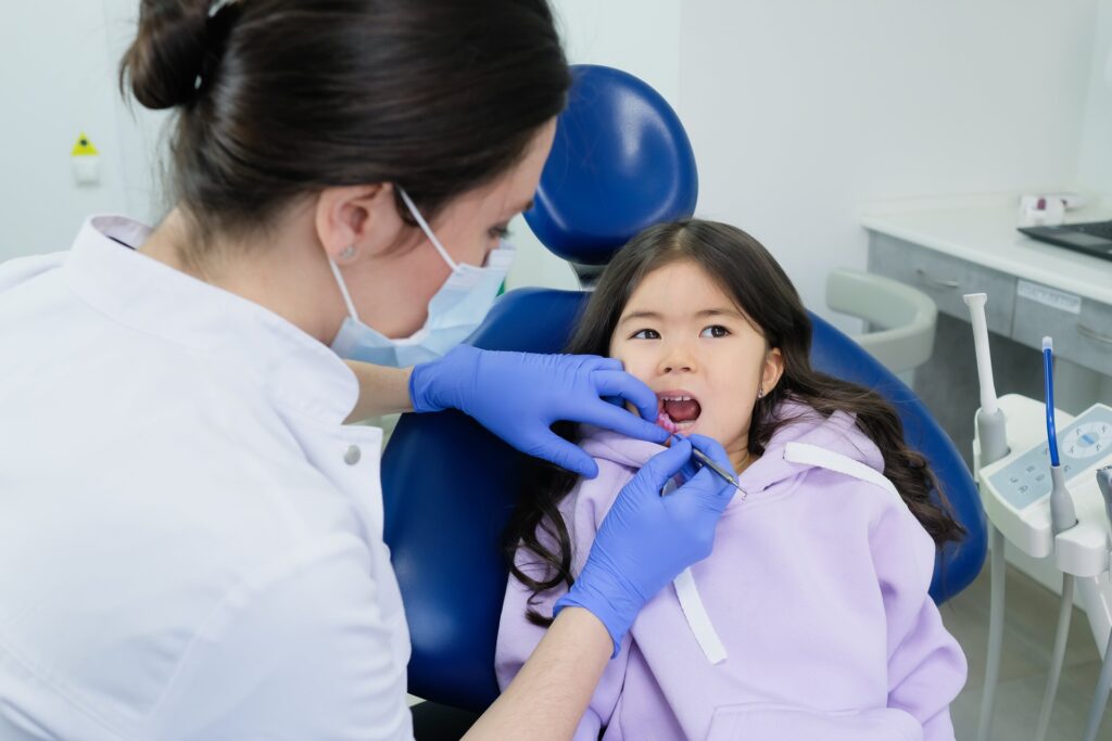 A dentist checking a young girl's teeth