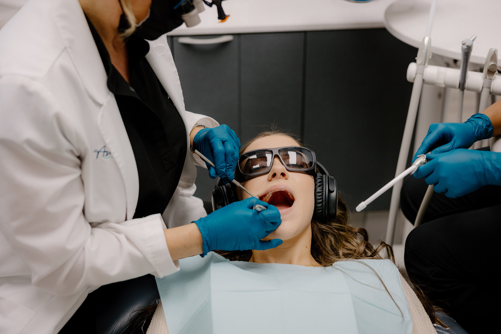 A dentist performing dental cleaning and exam on a patient