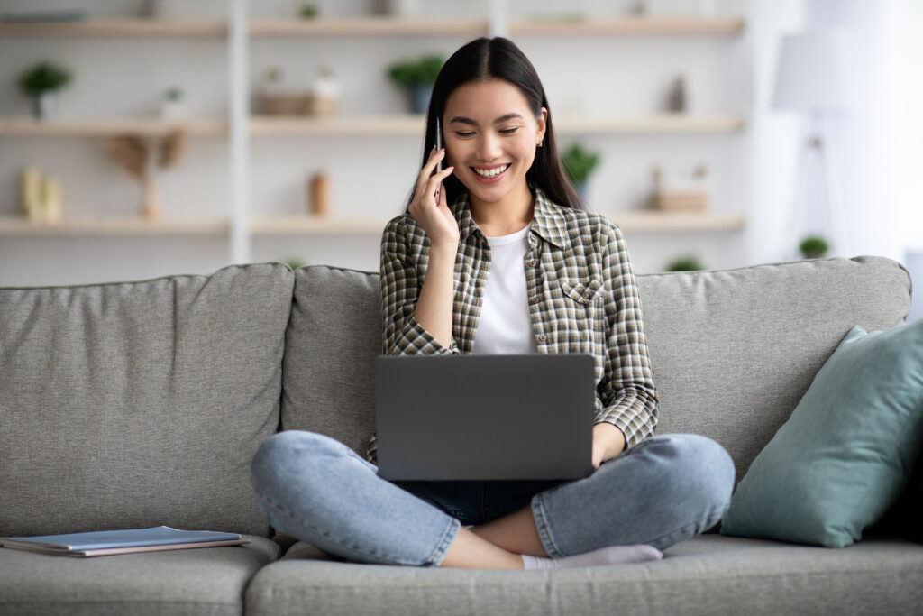 Girl talking on the phone while looking at her laptop