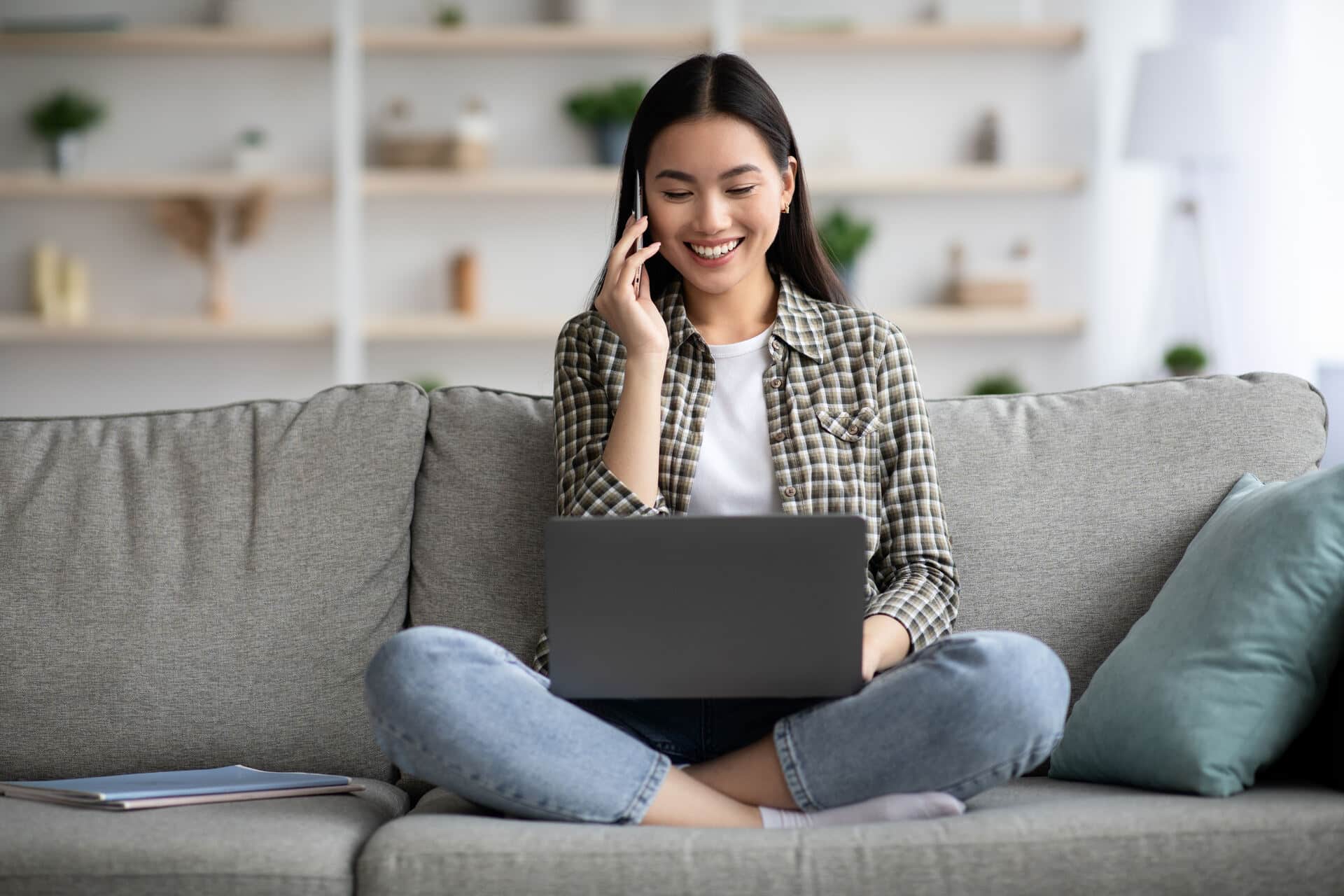 Girl talking on the phone while looking at her laptop