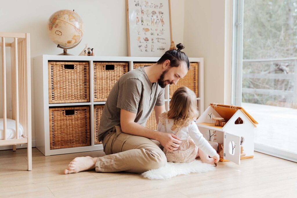 A father and a daughter playing with a doll house