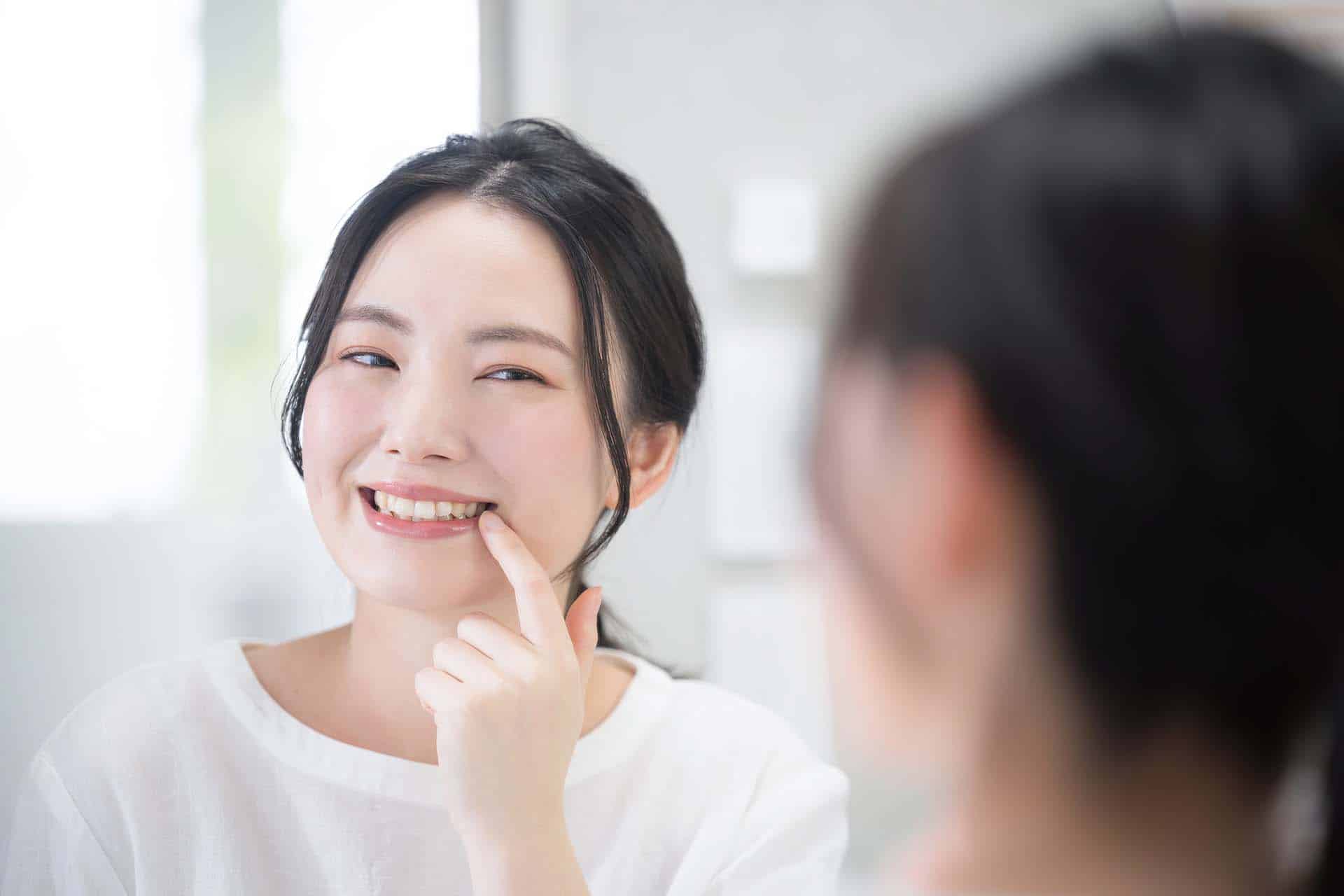 Cute woman looking at her teeth and whiteness while looking in t