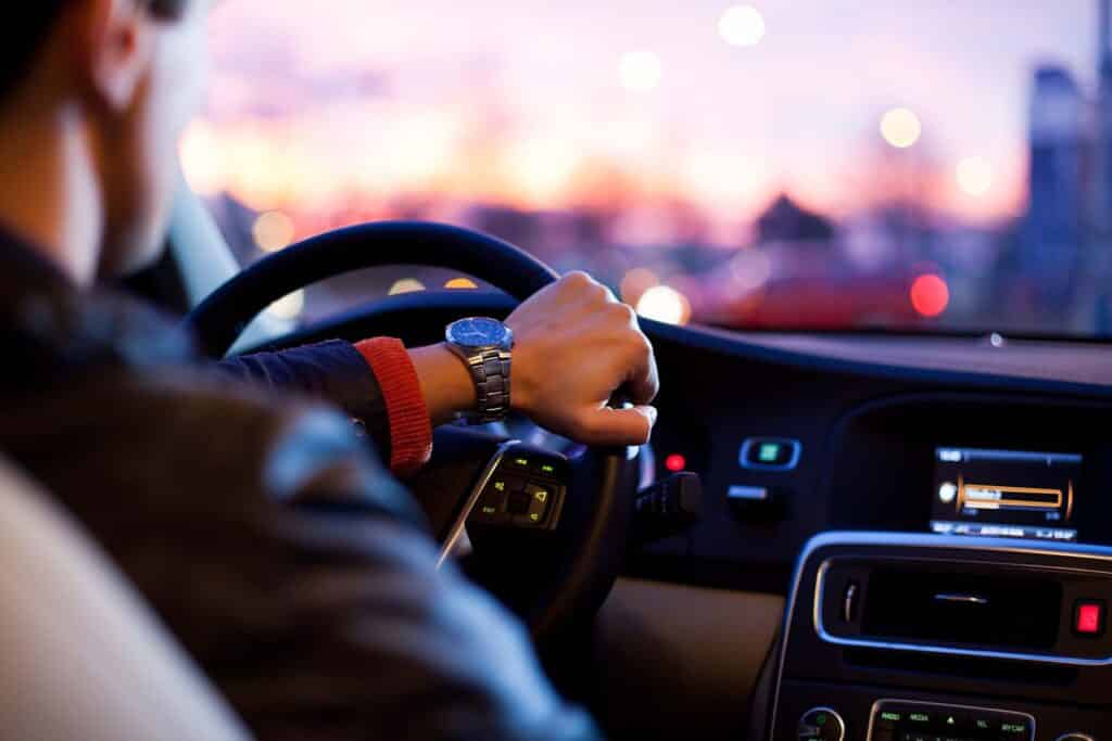 Driving a car at night - pretty, young woman driving her modern car at night in a city (shallow DOF; color toned image)