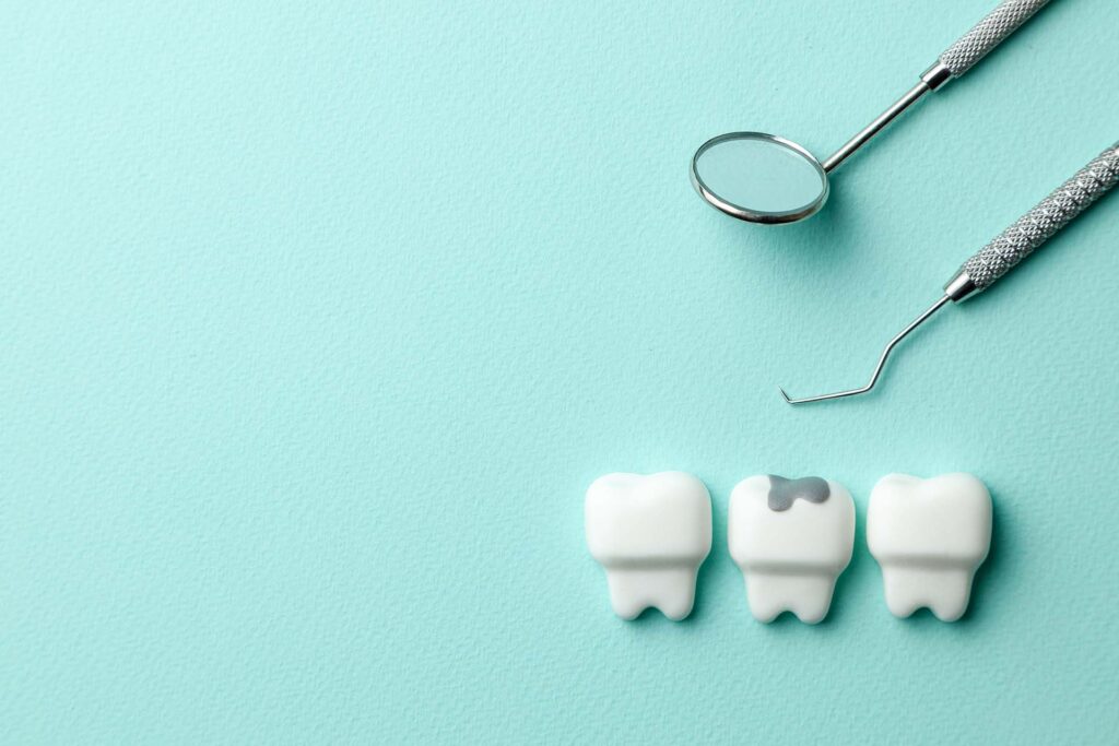 Healthy white teeth and tooth with caries on green mint background and dentist tools mirror, hook. Copy space for text