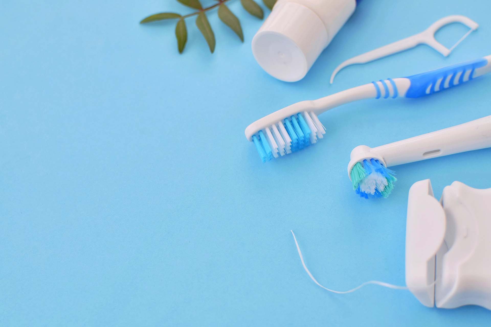 Toothbrushes, dental floss, and toothpaste on a blue background