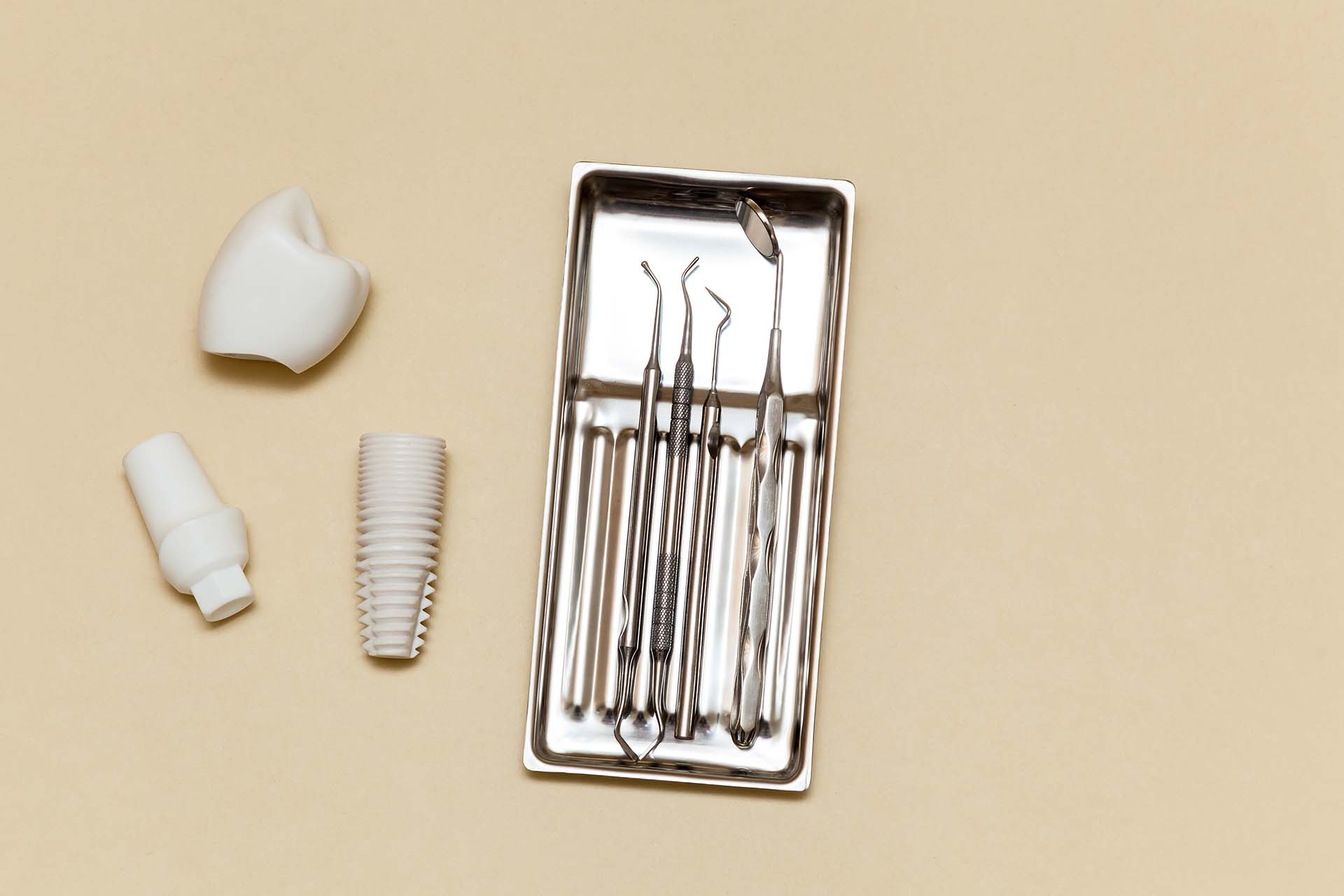 Dental implant, dental tools on a beige background. Dental implant model of artificial tooth. Concept of dentistry and medical instruments. Photo with place for your text and design.