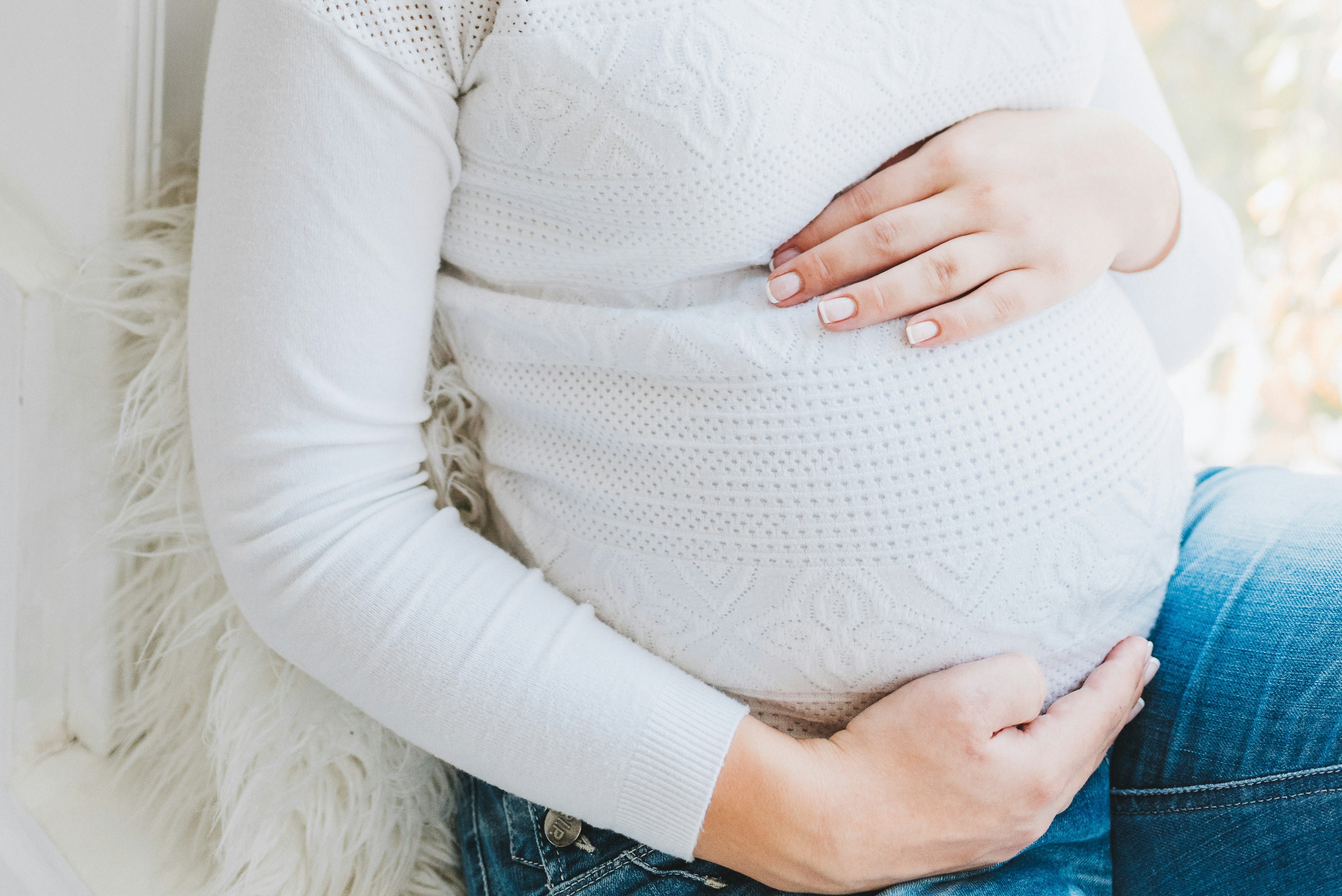 Pregnant woman holding her belly while preparing for a dental checkup at Aspire Dental Wellness in Charlotte, NC