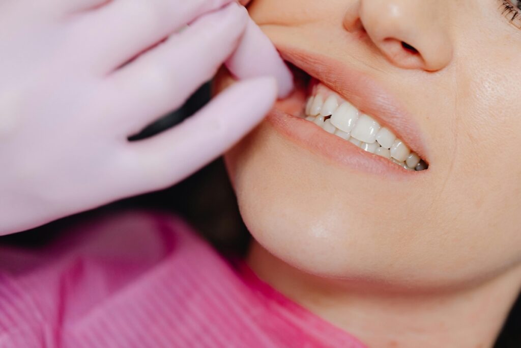 Dentist in pink gloves examining a patient's smile during a dental checkup at Aspire Dental Wellness