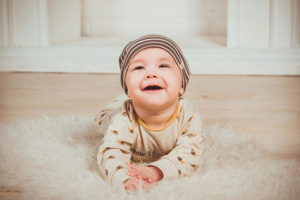 A smiling baby lying on a fluffy rug, showing early signs of healthy oral development.