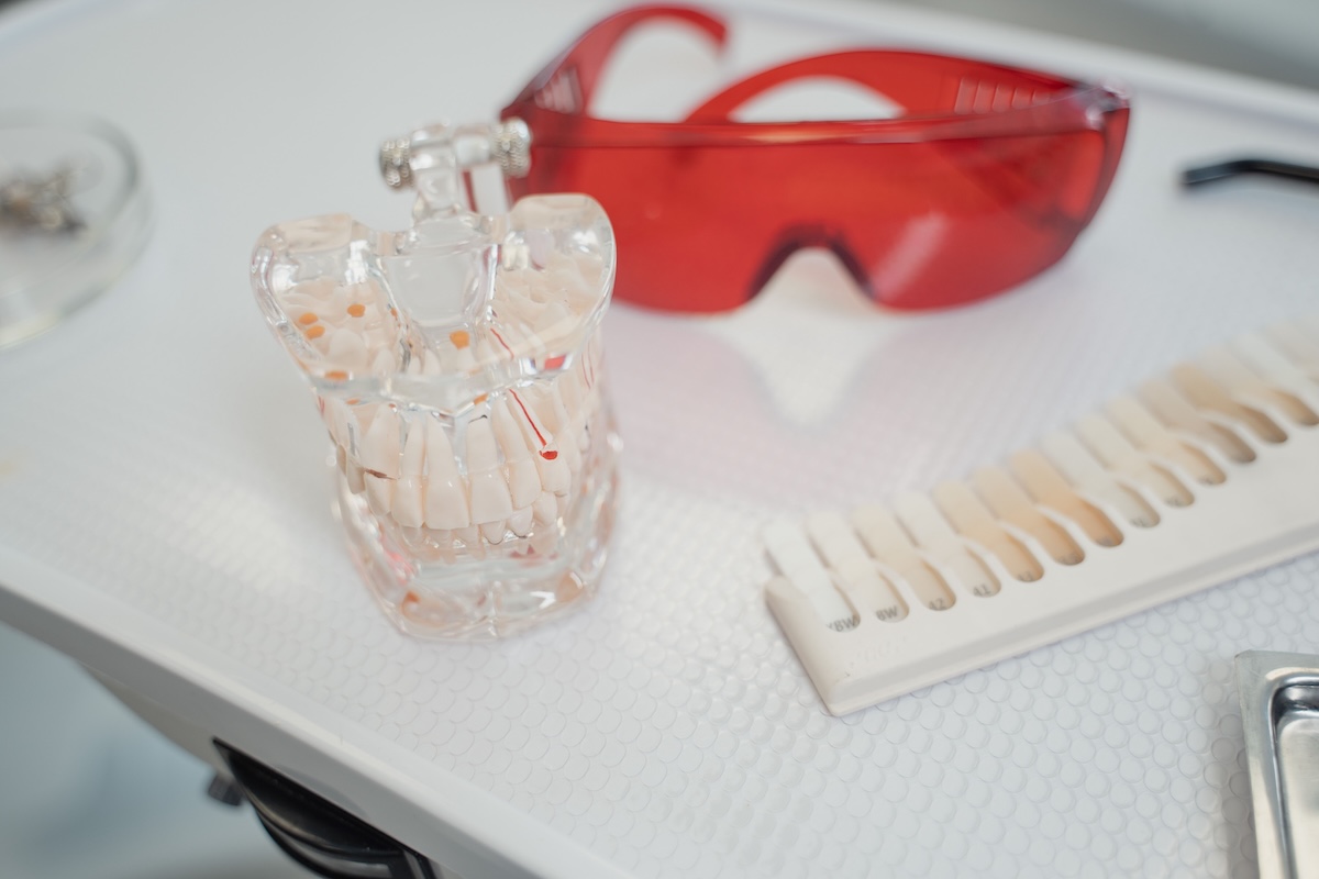 Dental model, shade guide, and curing light glasses arranged on a clinic tray